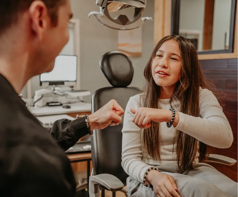 Child and dental professional sharing a fist bump after successful treatment